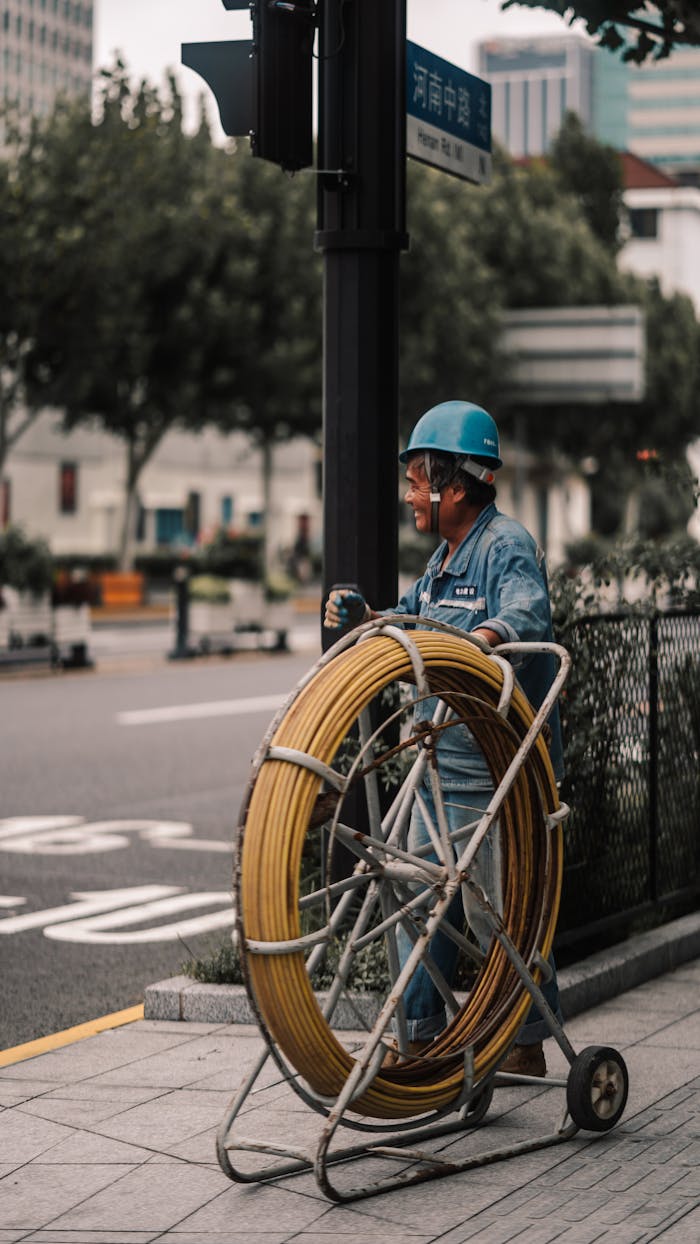 A construction worker manages cable equipment on a city street, showcasing urban development.